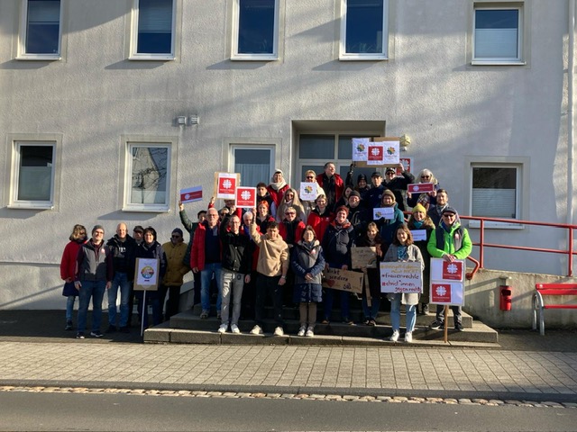 Mitarbeiter des Kooperationspartners Caritasverband sammeln sich vor der Dienststelle Bitburg, um gemeinsam am Demonstrationszug teilzunehmen